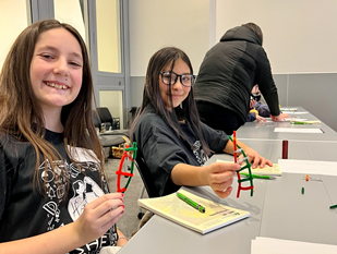 Two smiling, female students holding DNA structures